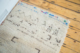 Thick, shaggy off-white wool pile with playful brown abstract patterns and colorful edge detail.