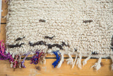 Thick cream wool pile and vibrant multi-color twisted fringe of this vintage Moroccan rug.