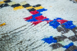 Plush wool pile of vintage Moroccan rug, featuring bold stepped patterns in blue, red, and gold.