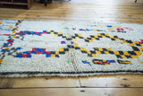 Shaggy ivory pile with playful stepped checker motifs in saffron, black, red, and blue.