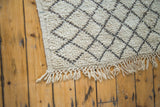 Textured ivory pile and charcoal lattice pattern on vintage Moroccan rug with fringe.