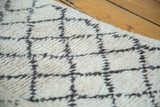 Textured ivory pile of vintage Moroccan rug, showing charcoal lattice design, visible edge.