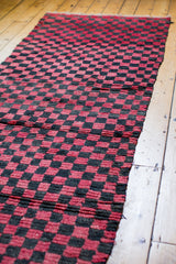 Textured red and charcoal checkered pattern on the vintage Moroccan runner.