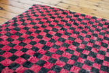 Moroccan runner's vibrant red and charcoal black checkered pile texture.