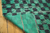 Furry mint green and charcoal Moroccan rug pile revealing its hand-woven back.