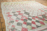 Faded red grapefruit, silvery grey, and ivory harlequin diamond motifs on a Moroccan rug.