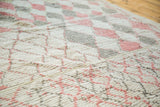 Vintage Moroccan rug's textured pile, showing faded ivory, red grapefruit, and grey diamond lattice.