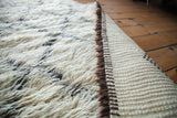 Fluffy ivory pile, charcoal lattice pattern, and flat woven back of a vintage Beni Ourain Moroccan carpet.
