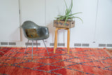 Textured vintage Moroccan rug pile showcasing cherry red abrashes and blue, saffron lattice.