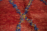 Textured deep red Moroccan rug pile with blue, soft blue, yellow lattice lines.