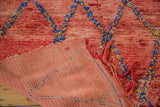 Vintage Moroccan rug's shaggy cherry red pile and hand-woven reverse with blue, yellow stitch pattern.