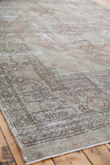 Distressed Oushak carpet corner with muted peach, ivory, and beige border patterns.