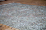 Textural distressed Oushak rug with soft peach and ivory faded geometric patterns.