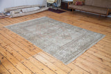 Distressed Oushak carpet with softened peach and ivory hues and faded traditional patterns.