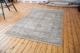 Distressed vintage Oushak carpet corner with faded peach and ivory geometric patterns.
