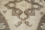 Vintage Oushak carpet close-up, whimsical geometric medallion in blanched ivory, charcoal, and pale mint.