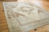 Vintage Oushak rug corner with pale mint border, blanched ivory field, and fringe.