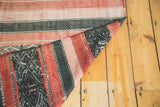 Folded vintage Jijim carpet revealing reversible wine red and charcoal geometric stripe.