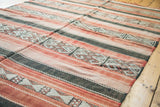 Repeating geometric motifs on a vintage Jijim carpet with wine red and charcoal stripes.