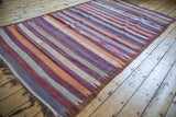 Detail of vintage Moroccan kilim, showing geometric stripes in orange, purple, grays, ivory, bronze.