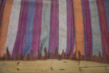 Jagged bronze edge and tribal geometric stripes of orange, purple, gray, ivory on vintage kilim.