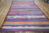 Angled detail of Vintage Moroccan Kilim rug: tribal orange, purple, gray stripes and fringe.