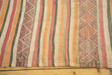 Close-up of vintage tribal kilim runner's geometric pattern in peach, red, and charcoal stripes.