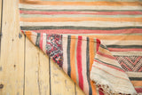 Folded corner of vintage kilim, showing multi-striped surface and geometric tribal reverse.