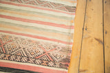 Detail of vintage kilim runner featuring tribal geometric pattern and muted ivory, grey, red stripes.