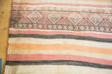 Tribal flatweave kilim runner with geometric patterns and striped bands in peach, ivory, charcoal.