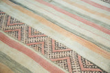 Geometric zigzag motif and striped bands in ivory, peach, and charcoal on a tribal kilim.