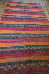 Vintage Kilim runner's geometric serrated patterns in charcoal, red, and orange stripes.