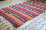Handwoven vintage kilim rug end, showing orange, red, charcoal stripes and geometric motifs.
