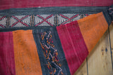 Close-up of vintage kilim rug's textured orange, red, charcoal stripes with geometric patterns.