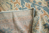 Vintage Oushak rug fold reveals woven geometric foundation in aqua teal, beige, bronze.