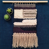 Multi-textured handwoven wall hanging with chunky purple, gray, off-white yarns, natural fringe.