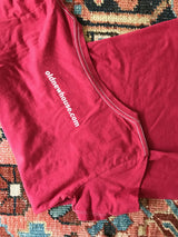 White website logo and contrast stitching on the back of a watermelon red t-shirt.