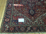 Antique Persian Heriz hand-knotted rug featuring a geometric medallion, ruby red and indigo palette, 8x11.
