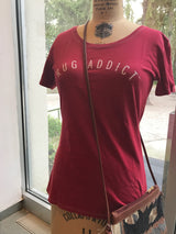 Watermelon red Rug Addict t-shirt styled on a dress form with a woven textile purse.