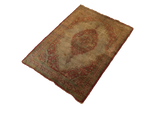 Angled view of the entire antique silk Tabriz rug with its rust medallion and soft green accents.