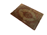 Angled view of an antique silk Tabriz rug highlighting its rust medallion and patinated field.