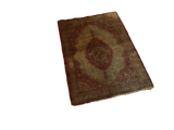 Angled view of an intricate antique silk Tabriz mat with a rust and green medallion.