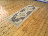 Softened gray field and light cream border of a vintage Turkish Oushak runner.