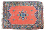 Plush vintage Moroccan carpet with blush red field, blue medallion, braided fringe, 6'8