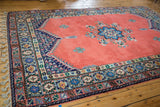 Vintage Moroccan carpet with blush red thick pile, braided fringe, and patterned border.