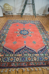 Thick pile blush red vintage Moroccan rug with blue medallion and braided fringe.