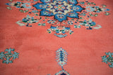 Close-up of vintage Moroccan carpet with thick, plush pile, blush red field, blue and white motifs.
