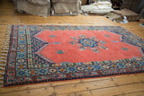 Plush blush red field, multi-color geometric border, and braided fringe of a vintage Moroccan carpet.