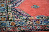 Vibrant geometric border patterns and plush blush red field of a vintage Moroccan carpet.