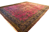 A vintage Meshed carpet's dynamic allover floral pattern in magenta, navy, and beige.